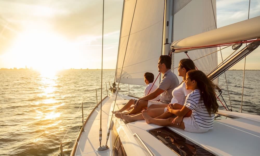 Carefree family travel adventures for young Latino parents with son and daughter relaxing on luxury yacht at sunset