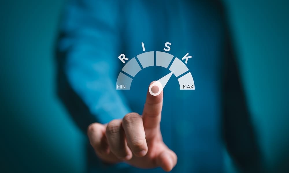 Risk management, businessman shows risk level indicator rating from min to max for assessing and controlling threats to an organization's capital, earnings, and operations. Business, finance concept.